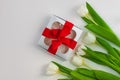 White tulip flowers and silver gift box on light background flat lay. Bouquet greeting card. Website banner top view Royalty Free Stock Photo
