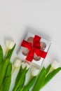 White tulip flowers and silver gift box on light background flat lay. Bouquet greeting card. Website banner top view Royalty Free Stock Photo