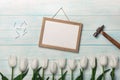 White tulips, chalk board, hammer and metal nails on blue boards . Mother`s day