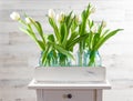 White tulips in a crate of blue mason jars