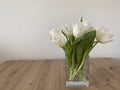 White tulips in glass vase on the wooden table