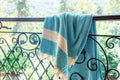 A white and turquoise Turkish peshtemal / towel on a wrought iron railings with blurry nature in the background. Royalty Free Stock Photo