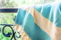 A white and turquoise Turkish peshtemal / towel on a wrought iron railings with blurry nature in the background. Royalty Free Stock Photo