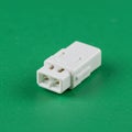 White two-pin electrical connector on a smooth green surface. The connector features Royalty Free Stock Photo