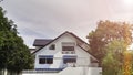 White two-storey house with green trees surrounding it.