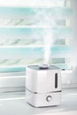 The white ultrasonic humidifier on a window moistens dry air Royalty Free Stock Photo