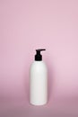 White unbranded plastic dispenser pump bottle on pink background. Cosmetic package mockup, liquid soap flacon, hand Royalty Free Stock Photo