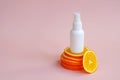 White unbranded plastic spray bottle and orange slices podium on pink background. Natural organic spa cosmetics and liquid