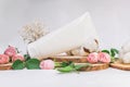 White unbranded tube for cosmetics with wood cuts, small pink roses and cotton flowers on white background. Natural cosmetic