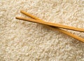 White uncooked, raw long grain rice full frame with chopsticks top view flat lay from above