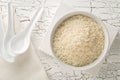 White uncooked, raw long grain rice in white bowl with spoons on rustic white wooden table top view flat lay from above Royalty Free Stock Photo