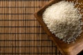 White uncooked, raw long grain rice in wooden bowl on bamboo mat with copy space top view flat lay from above Royalty Free Stock Photo