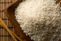 White uncooked, raw long grain rice in wooden bowl with chopsticks on bamboo mat top view flat lay from above Royalty Free Stock Photo