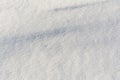 White uneven snow texture with embossed shadows. Abstract background with snowy surface in spring time