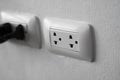 White universal electricity sockets plug on a white wall. Royalty Free Stock Photo