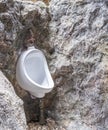 White urinal for male decoration on wall mountain in natural hill. strange idea install urine flush