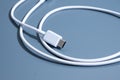 White USB cable for charging and data transfer coiled on blue background Royalty Free Stock Photo
