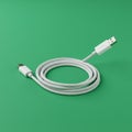 White USB cable on a plain green background. The cable is coiled neatly with two Royalty Free Stock Photo