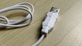 White USB-A Cable Plug and Coiled Cord on Wood Desk Surface Royalty Free Stock Photo