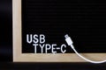 White usb type-c connector with a wire on the background of a black felt board with an inscription. Minimalism. A modern way to Royalty Free Stock Photo