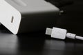 White usb type-c plug on a black background next to the white power supply and fast charger with usb type-c connector. The concept Royalty Free Stock Photo