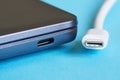 White USB type-c plug and its corresponding port on a modern laptop - ultrabook on a blue background. Modern information