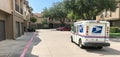 White USPS truck stops at apartment building complex on sunny da