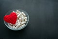 White veg capsules and red thread heart in glass bowl on black b Royalty Free Stock Photo