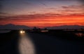 a car driving down a country road at night with the sun setting in the distance Royalty Free Stock Photo