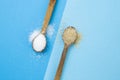 white versus brown sugar crystals on wooden tea spoons, and blue background Royalty Free Stock Photo