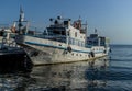 White vessel ships boats with blue stripes on pier in bay of lake baikal in light of sun with reflections in water Royalty Free Stock Photo