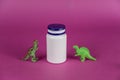 White vial and dinosaur miniatures against a purple background. Small green figures of predatory animals standing on their hind