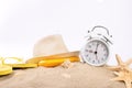 White vintage alarm clock with beach items on the sand Royalty Free Stock Photo