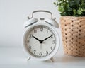 The white vintage alarm clock showing time 10 0`clock in the morning next to the window under morning light. Royalty Free Stock Photo