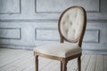 White vintage chair standing in front of a light wall with mouldings on wooden parquet floor. Royalty Free Stock Photo