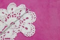 White vintage crochet doily. Cotton yarn for knitting, crochet hook on the pink plush background