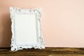 White vintage photo frame on old wooden table over pink wall background Royalty Free Stock Photo