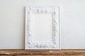 White vintage photo frame on old wooden table over white wall ba Royalty Free Stock Photo