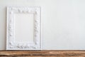 White vintage photo frame on old wooden table over white wall ba Royalty Free Stock Photo