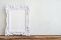 White vintage photo frame on old wooden table over white wall ba Royalty Free Stock Photo