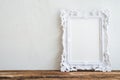 White vintage photo frame on old wooden table over white wall ba Royalty Free Stock Photo