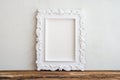 White vintage photo frame on old wooden table over white wall ba Royalty Free Stock Photo
