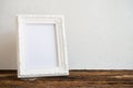 White vintage photo frame on old wooden table over white wall ba Royalty Free Stock Photo