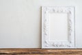 White vintage photo frame on old wooden table over white wall ba Royalty Free Stock Photo