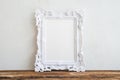 White vintage photo frame on old wooden table over white wall ba Royalty Free Stock Photo