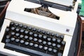 A white vintage printing press is sold at a flea market in the rain