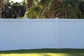 White vinyl picket fence on green lawn surrounding property grounds for backyard protection and privacy