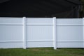 White vinyl picket fence on green lawn surrounding property grounds for backyard protection and privacy