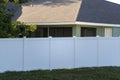 White vinyl picket fence on green lawn surrounding property grounds for backyard protection and privacy