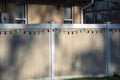 White vinyl picket fence on green lawn surrounding property grounds for backyard protection and privacy